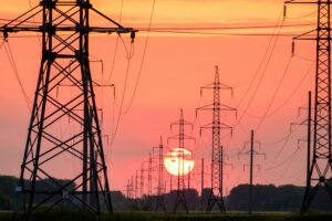 view of power lines in the sunset with the moon shining. 