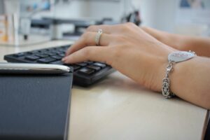 Medical Disclaimer: Image of woman with a medica alert bracelet typing on a keyboard. 
