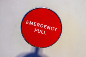 Image of a red emergency pull button against a white wall