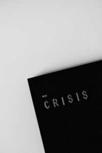 Image of a black journal with the word crisis on it on a white table