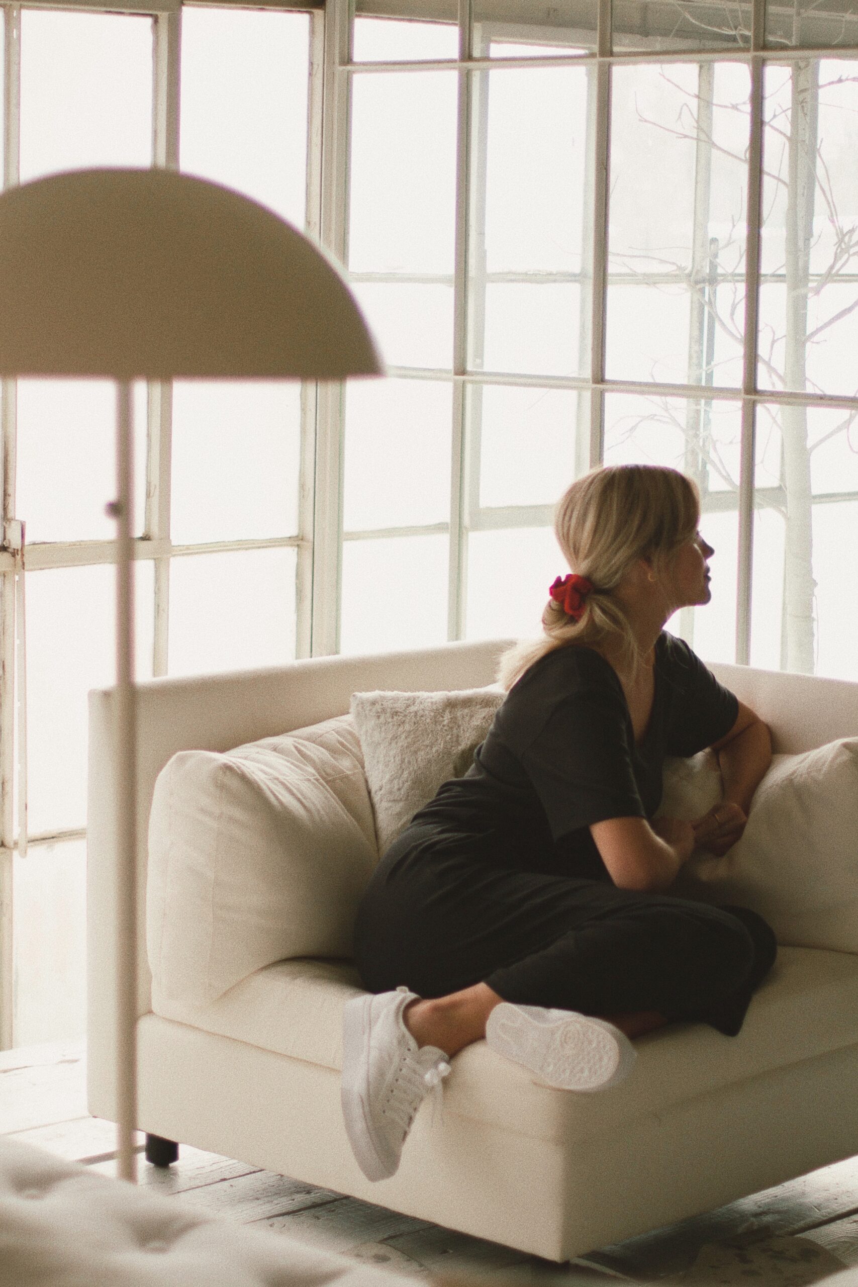 Image of woman sitting in white comfy chair looking out the large glass windows
