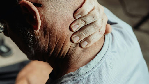 Image of man holding the back of his neck in discomfort
