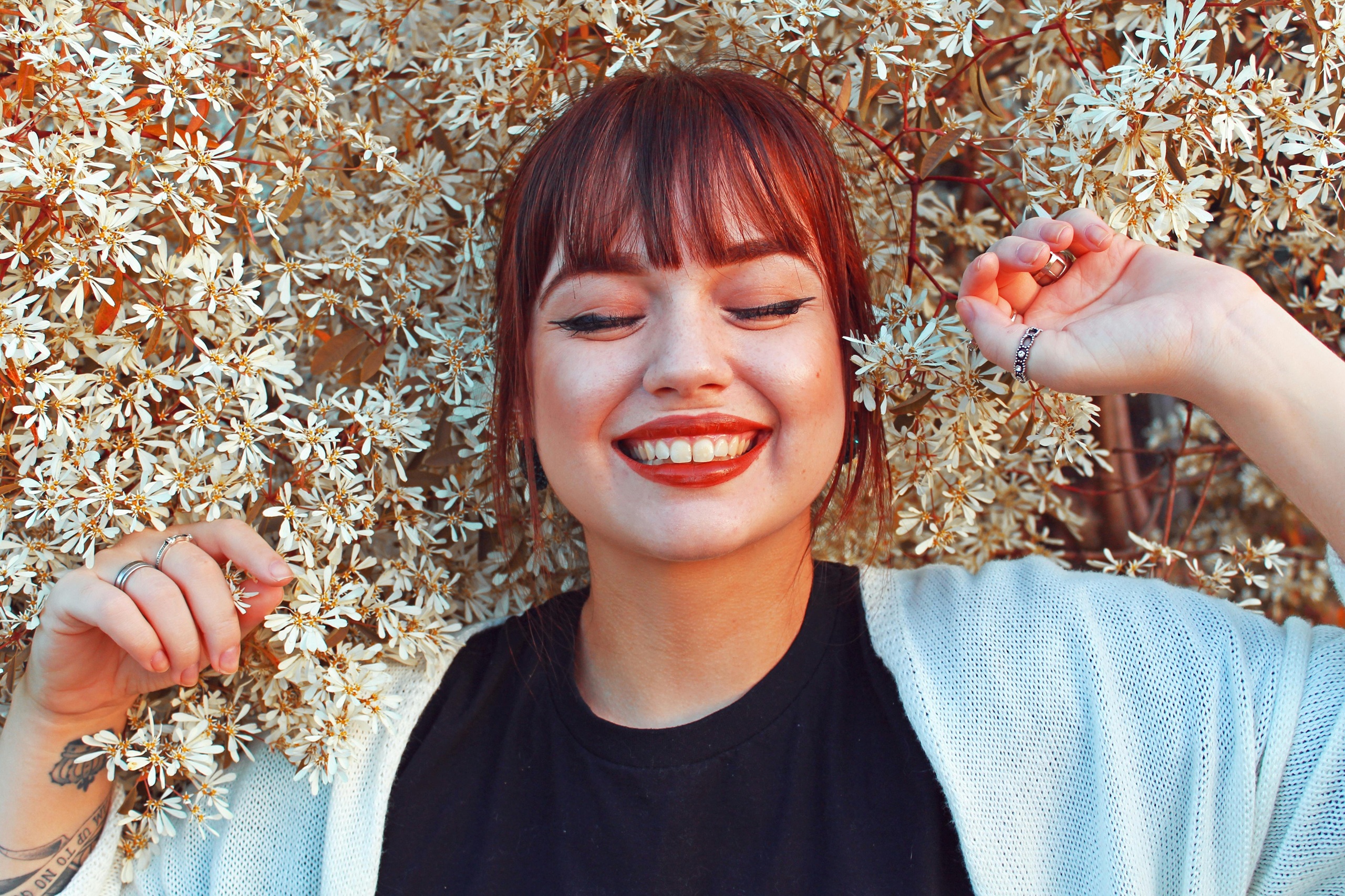 Image of woman laying in field of flowers with big smile on face